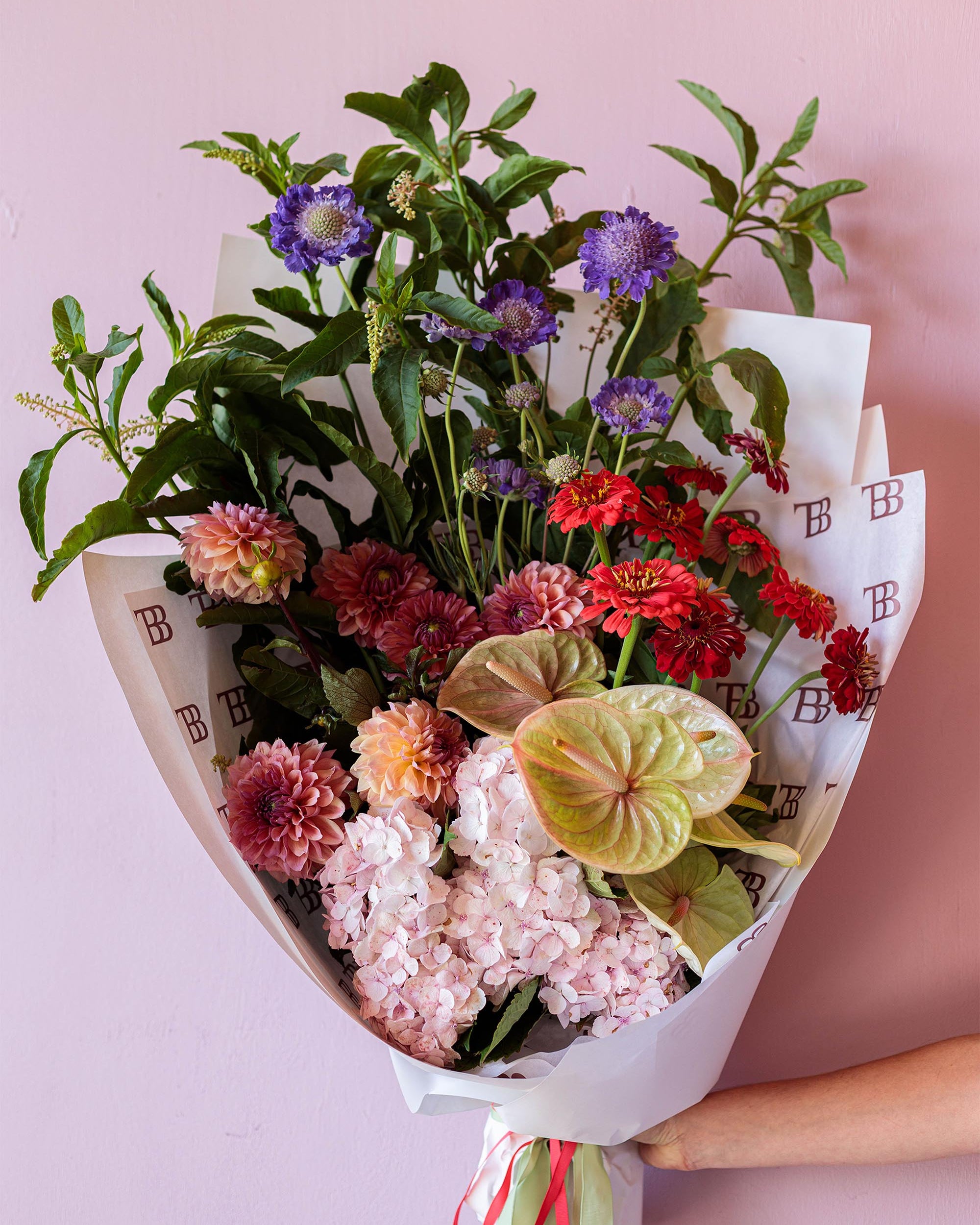 Bouquet of colorful flowers wrapped in paper with a pink background